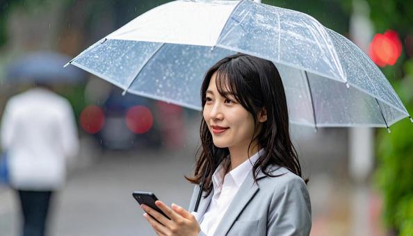 傘をさしてスマホを使う若い日本人女性 傘をさしてスマホを使う若い日本人女性の写真