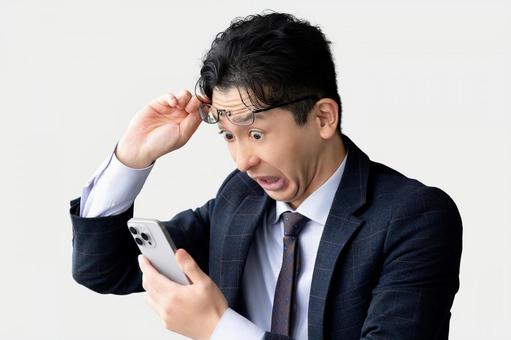 スマホを見て驚く男性ビジネスマン スマホを見て驚く男性ビジネスマン 男性,スマホ,スマートフォンの写真素材