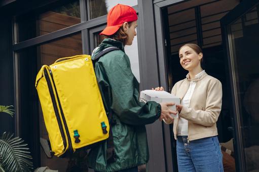 女性客にピザを届けに来たフードデリバリーの男性 配達,フードデリバリー,デリバリーの写真素材