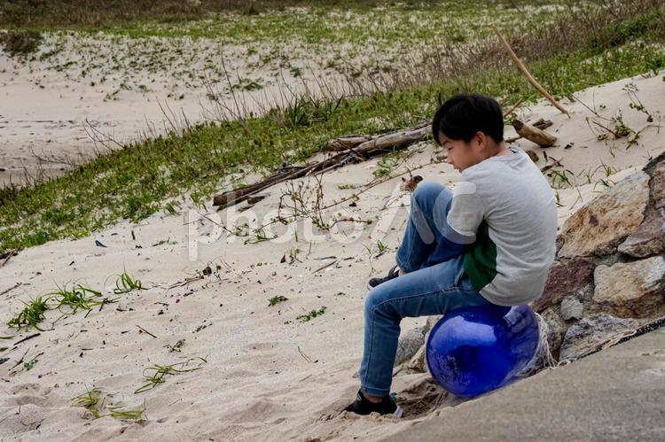 ※＜素材＞ビンに座って海を見詰める少年 子供,男性,人物の写真素材