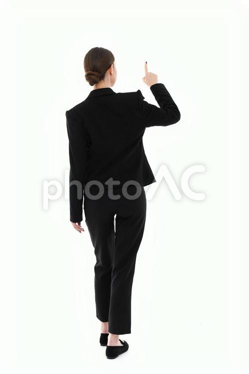 歩きながら指さす女性の後ろ姿 女性,後ろ姿,立つの写真素材