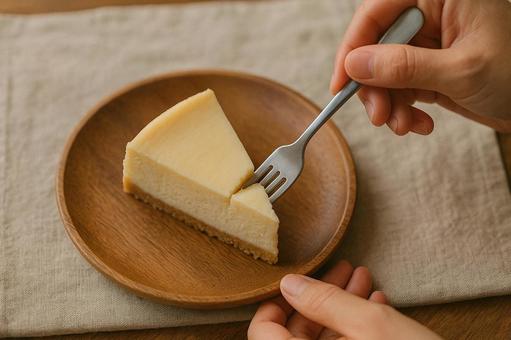 フォークでチーズケーキを一口すくう手元 フォークでチーズケーキを一口すくう手元の写真