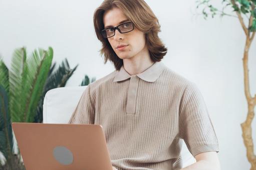 椅子に座って膝の上でノートパソコンを使うカメラ目線の若い男性 男性,外国人,欧米人の写真素材