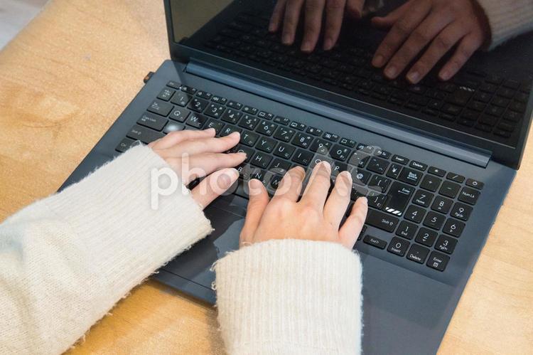 ノートパソコンを操作するニットを着た女性 パソコン,リモートワーク,ノートパソコンの写真素材