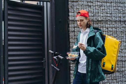 サラダを食べているフードデリバリーの男性の写真