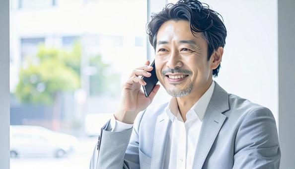 笑顔で電話する中年 笑顔で電話する中年の写真