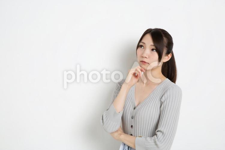 アゴに手をあて悩んでいるポニーテールの女性（コピースペース） 悩み,悩む,女性の写真素材