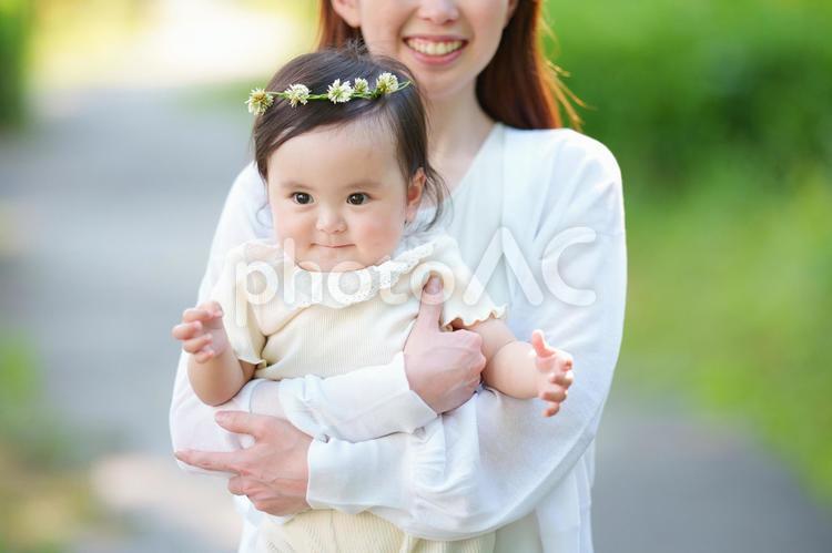 公園でお母さんに抱っこされているシロツメクサの花冠をつけた女の子の赤ちゃん 赤ちゃん,お母さん,日本人の写真素材