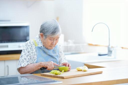 真剣な顔でリンゴを切る高齢女性 女性,リンゴ,切るの写真素材