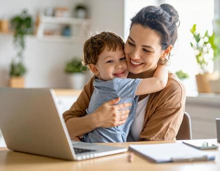 在宅ワーク中に子どもとハグする母親の写真
