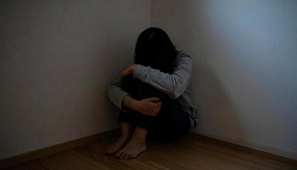 膝を抱え込み悩む女性 膝を抱え込み悩む女性の写真
