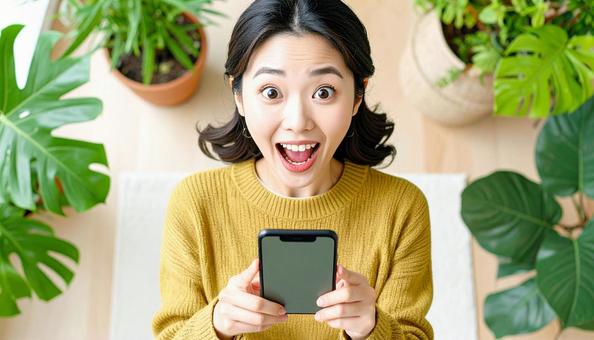 携帯電話を見て驚いている女性 携帯電話を見て驚いている女性の写真