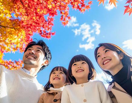 青空の下で秋の紅葉を仲良く鑑賞する家族 青空の下で秋の紅葉を仲良く鑑賞する家族の写真