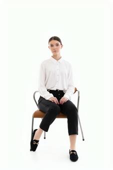 真顔で座る白シャツの女性 真顔で座る白シャツの女性の写真