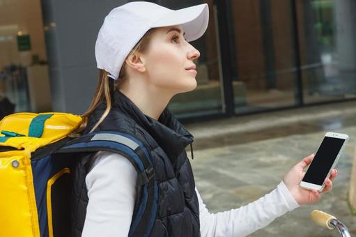 スマートフォンを使うフードデリバリーの女性 配達,フードデリバリー,デリバリーの写真素材