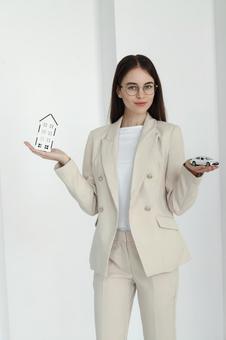 女性スタッフと手のひらの家と車模型 保険業,事務職,接客業の写真素材