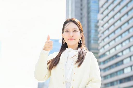 ビル街でグッドポーズをする女性 ビル街でグッドポーズをする女性の写真