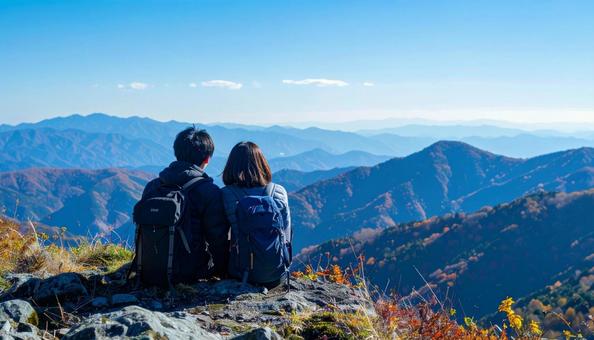登山中に岩の上に座って休憩するカップル 登山中に岩の上に座って休憩するカップルの写真