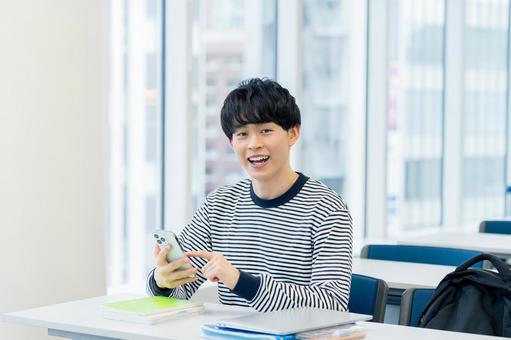 教室でスマホを見る大学生 スマホ,笑顔,大学生の写真素材