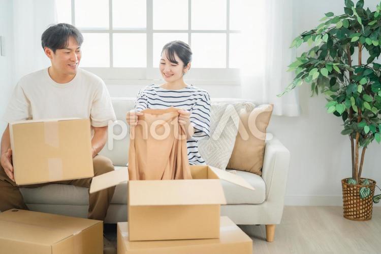 ダンボールの中の洋服を持つ男女（引越し） 引越し,荷物,夫婦の写真素材