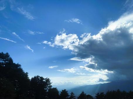 雲間から光が差し込む青空と森の風景 青空,雲,光の写真素材