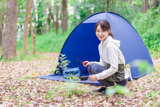 ソロキャンプを楽しむ若い女性 ソロキャンプを楽しむ若い女性の写真