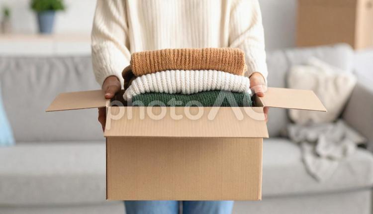 段ボールに古い衣類を詰めた女性の手 不用品,箱,女性の写真素材