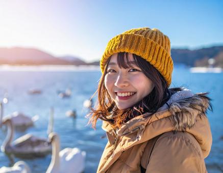 冬の湖・白鳥を観察する彼女の写真