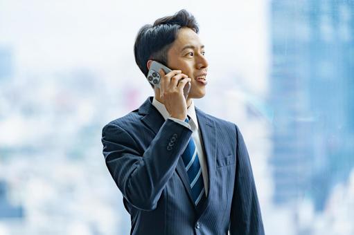 高層ビルで電話をするビジネスマン 高層ビルで電話をするビジネスマン ビジネスマン,男性,スーツの写真素材