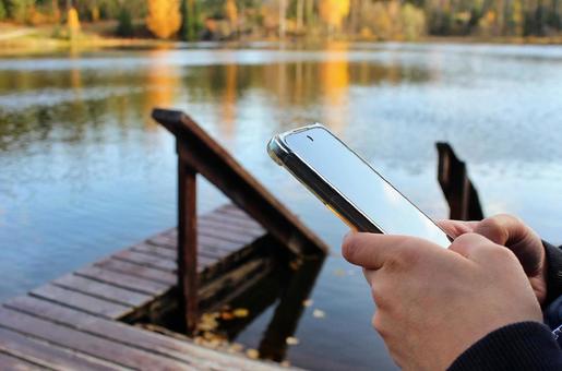 北欧の秋の湖と携帯を操作する手元 北欧の秋の湖と携帯を操作する手元 スマホ,sns,スマートフォンの写真素材