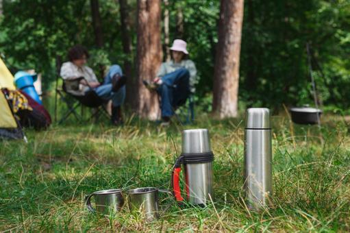 並ぶキャンプ道具と焚き火 水筒,マグカップ,鍋の写真素材