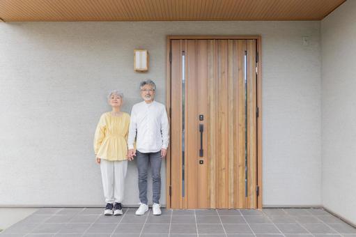 笑顔で住宅の前に立つシニアカップル 笑顔で住宅の前に立つシニアカップル シニア,老人ホーム,カップルの写真素材