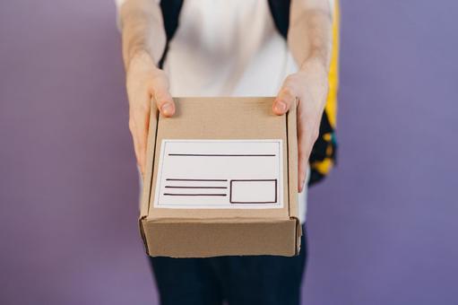 段ボール箱を差し出す配達員の男性の手元 配達,デリバリー,配送の写真素材