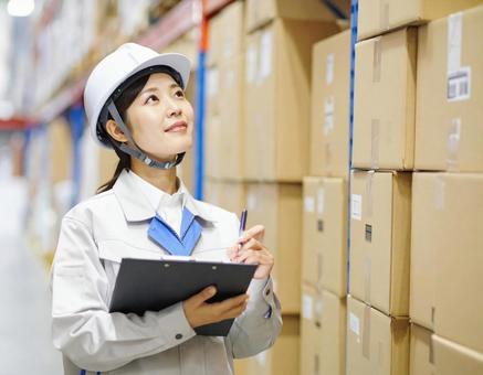 倉庫で在庫をチェックする女性作業員 倉庫で在庫をチェックする女性作業員の写真
