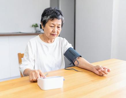 血圧を測り不安そうな表情するシニア女性 血圧を測り不安そうな表情するシニア女性の写真