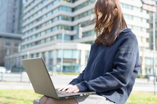 ベンチに座ってパソコンを操作する女子高生 ベンチに座ってパソコンを操作する女子高生 高校生,女子高生,女性の写真素材