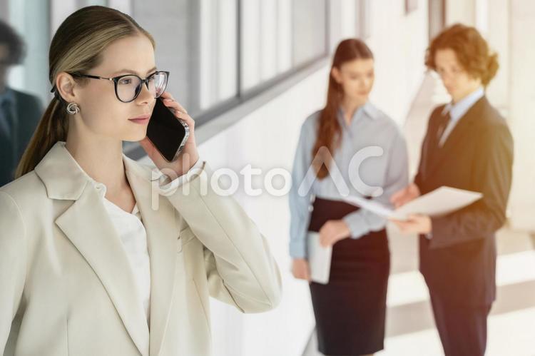 オフィスの廊下で立ち話する男女と電話している女性 ビジネス,グループ,ビジネスマンの写真素材