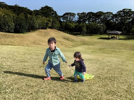 <素材>公園の芝生でそり遊びをする兄弟 <素材>公園の芝生でそり遊びをする兄弟 子供,男性,人物の写真素材