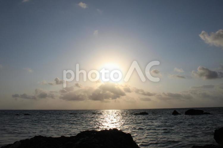 紺色の空と岩のある浜辺を照らす朝日 空,海,太陽の写真素材