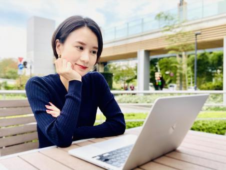 屋外でオンライン英会話をする女性 屋外でオンライン英会話をする女性 女性,笑顔,パソコンの写真素材