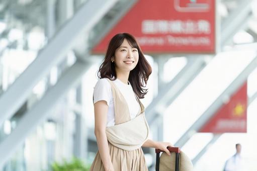 空港の入り口に立つ旅行中の女性 空港の入り口に立つ旅行中の女性の写真