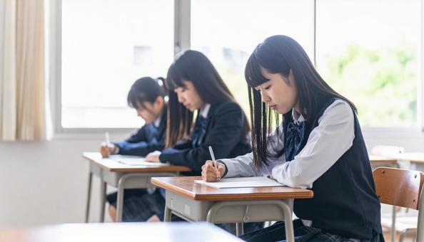 教室で勉強に集中する女子学生たち 教室で勉強に集中する女子学生たちの写真