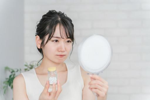 肌荒れに悩むサプリメントを持つ女性 肌荒れに悩むサプリメントを持つ女性 肌荒れ,ニキビ,悩むの写真素材