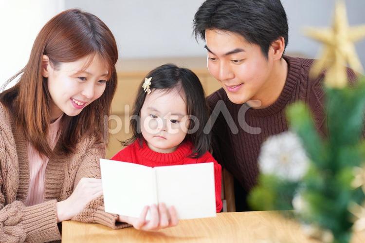 女の子に絵本の読み聞かせをする家族 家族,人物,男性の写真素材