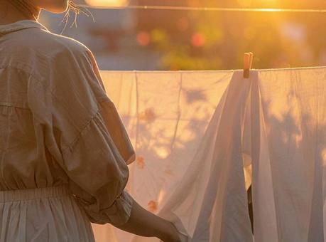 夕暮れ時に洗濯物を取り込む女性の写真