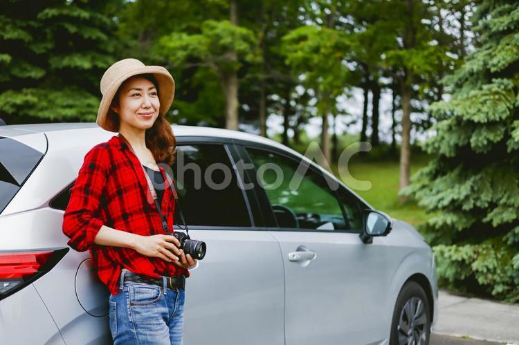 車とカメラを持つ女性 カメラ,旅,一眼レフの写真素材
