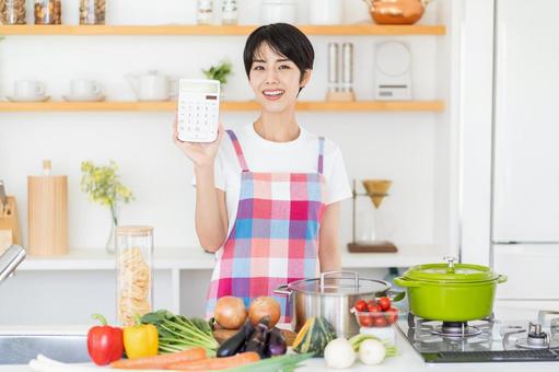 キッチンで電卓を持つ主婦。 キッチンで電卓を持つ主婦。の写真
