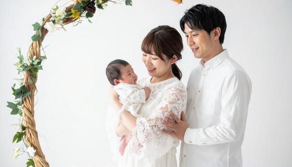 産着に包まれて笑顔の赤ちゃんと家族の写真