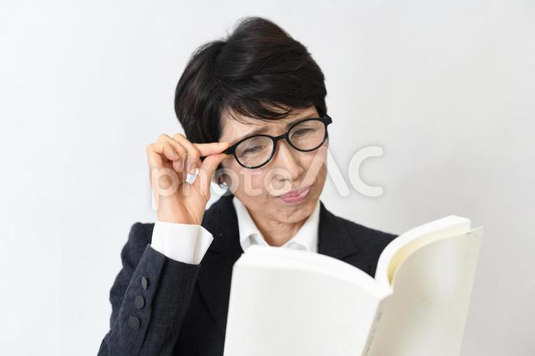 本を見る老眼や近眼に悩む中高年の女性 中年,中高年,ミドルの写真素材
