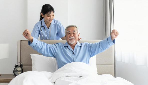 シニアの起き上がりを補助する介護士の写真